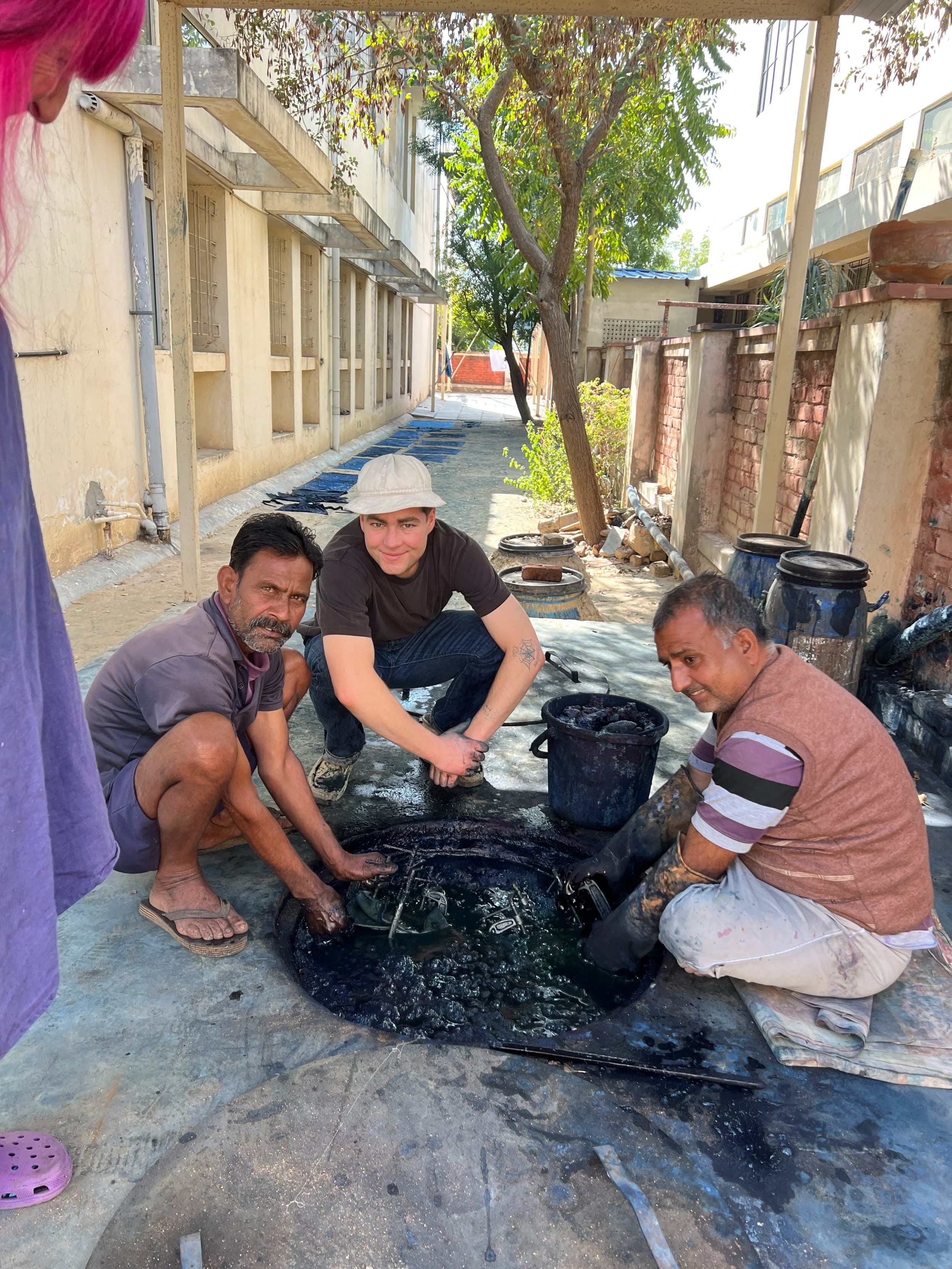 Three artisans working at indigo vat